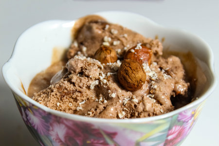 Chocolate ice cream with hazelnuts close-up, which is sprinkled with nut crumbs. Selective shot.の写真素材