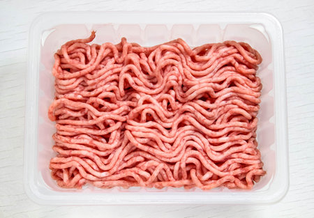Fresh minced pork in a food substrate on a white background. The view from the top.