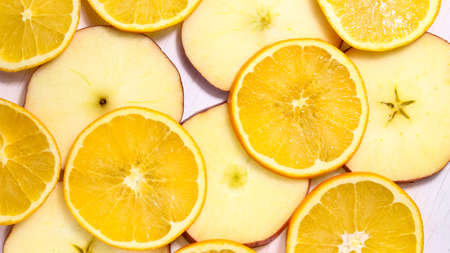 Swirling background of sliced oranges and apples on a white background. Vegetarian background. The...