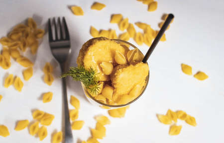 A glass cup with nuggets and pasta, with a drinking straw. Creative still life. Top view.の写真素材