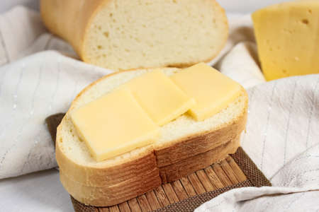 Still life with a white sliced loaf of cheese on a light background. Nutritious food that is...