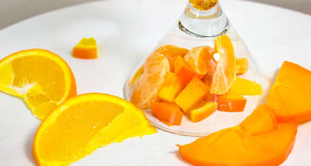 A glass of spilled orange fruit, cut into chunks, has fallen on its side. Selective shot.の写真素材