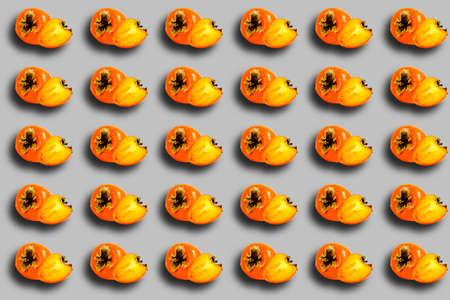 A pattern of ripe persimmons on a gray background. Banner, the concept of dietary food. Prints,...
