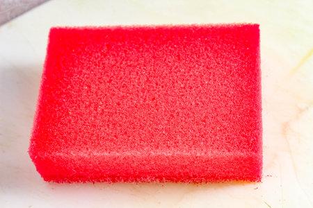 Household sponge of red color on a light background. Close-up.の写真素材