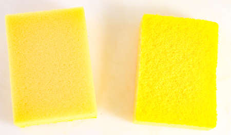 Household sponges of yellow color on a light background. Close-up.