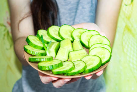 A plate of fresh, beautifully arranged cucumbers, held by the hands. Blurry. Close-up, selective shot.の写真素材