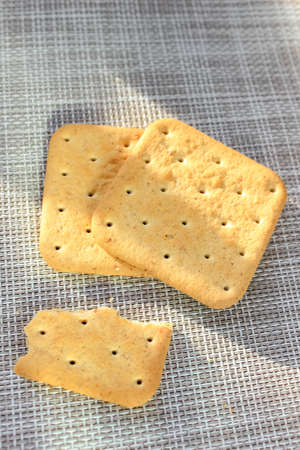 A few whole and broken crackers on the table. Vertical frame, top view.