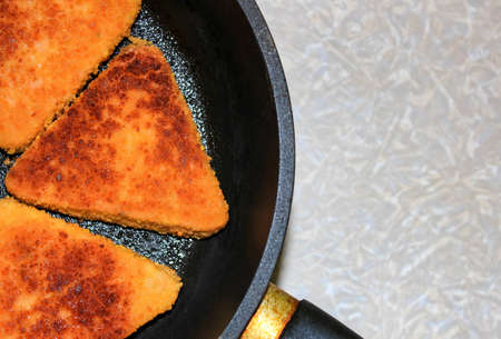 Cutlets of triangular shape are fried in a frying pan. Top viewの写真素材