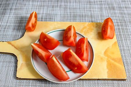 Sliced tomatoes lie on a plate and on a cutting board. Close-up.の写真素材