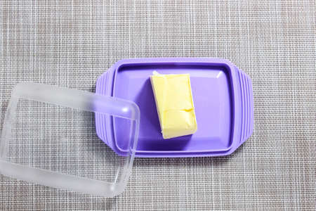 A small piece of butter in a purple butter dish. Top view.