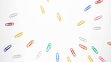 Stationery paper clips of different colors on a white background. Top view.