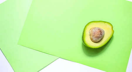 Half an avocado with a stone on a green background. Top view.