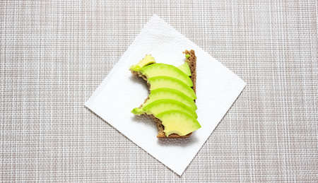 A bitten-off black bread sandwich with avocado. Top view.