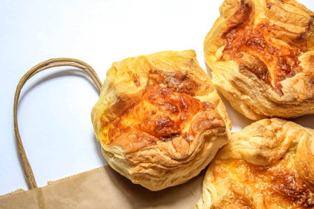 Fresh baked khachapuri with cheese lie on a paper grocery bag. Top view.