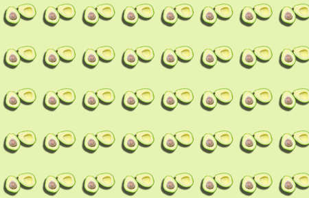 A pattern of two avocado halves with a shadow on a green background. Prints, templates.