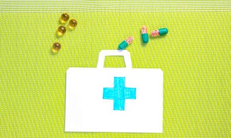 Various medicines, vitamins, pills that fall into a paper first aid kit. Top view.