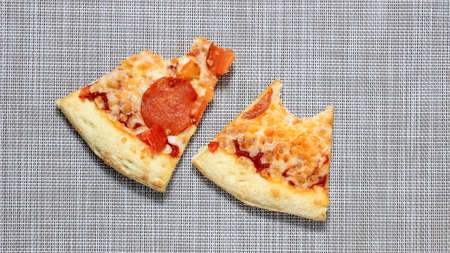 Two bitten pieces of pizza on the table. Top view.