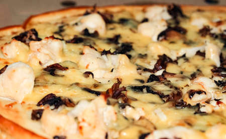 Part of a pizza with chicken and mushrooms in close-up. A selective shot.の写真素材