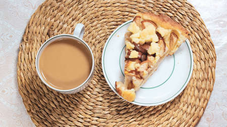 Coffee with milk in a mug, next to a cut piece of charlotte on a saucer. Top view.の写真素材