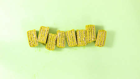 Pieces of matcha waffle covered with icing, a healthy dessert, on a green background. Healthy food....