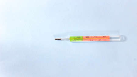A mercury thermometer for measuring temperature turns on a blue surface. Top view.の写真素材