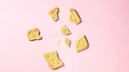 A broken cracker into small pieces on a pink background. Top view.の写真素材