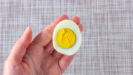 Half of a boiled egg in your hand. A quick snack. Top view.