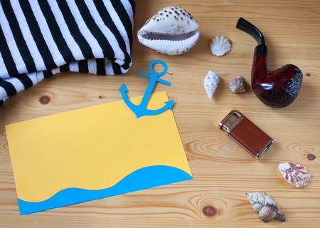 Congratulations on the day of the seafarer. Smoking pipe, card with anchor, seashells on a wooden tableの写真素材