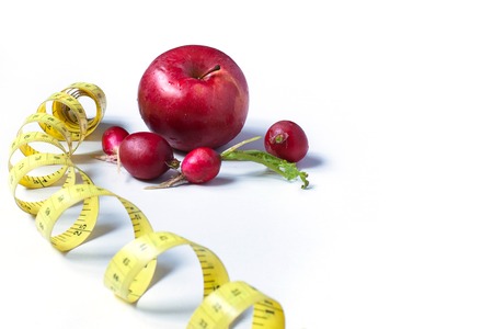 red radishes, centimeters and apple on white background.の写真素材