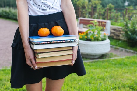 Female hands holding stack of books. Young girl with schoolbook. The concept of the beginning of the...