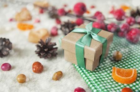 Christmas composition with gift box decorated green ribbon. Still life with snow, colorful candy and...