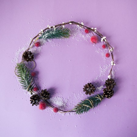Handmade christmas wreath with copy space for text on purple color background. Top view