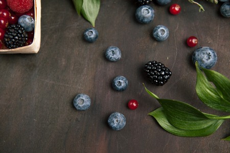 Blackberries and bilberries with leaves on the wooden table. Top viewの写真素材