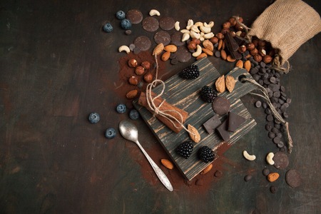 Handmade chocolate with nuts and berries on a wooden background. Top viewの写真素材