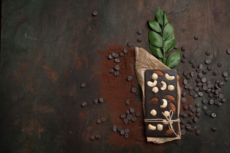 Handmade chocolate with nuts and branch of the leaves on a wooden background. Top viewの写真素材