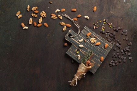 Assorted mixed nuts and chocolate on a wooden cutting board. Top view with copy spaceの写真素材