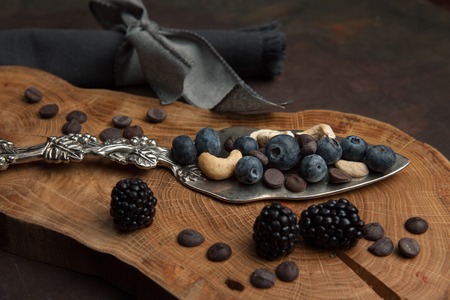 Spatula for cake with nuts, chocolate and berries on the wooden background. Close up. Restaurant dessert menu background.の写真素材