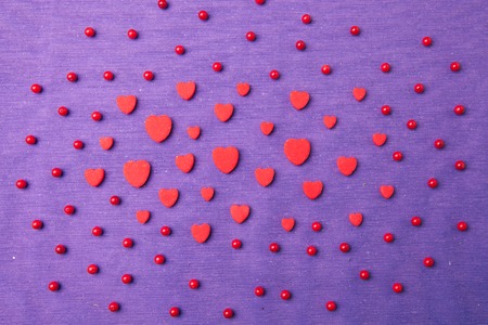 Red small hearts on a purple background. Top view