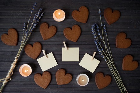 Heart gingerbread cookies with empty notes and candles on a wooden background. Concept the Feast Day of Holiday Valentine's Day. Top view.の写真素材