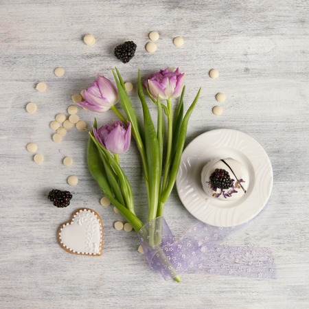 Cake on white wooden table and a bouquet of tulip, Valentines Day background, top view. Cookie shaped heart and blackberry berriesの写真素材