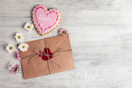 Envelope with wax seal on wooden background. Flowers tulips and heart shaped gingerbread cookie. Concept the Feast Day of Holiday Valentine's Day, Mother's day. Top view with copy spaceの写真素材