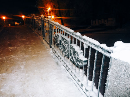 Snow on the railing of the bridge at night in the city.の写真素材