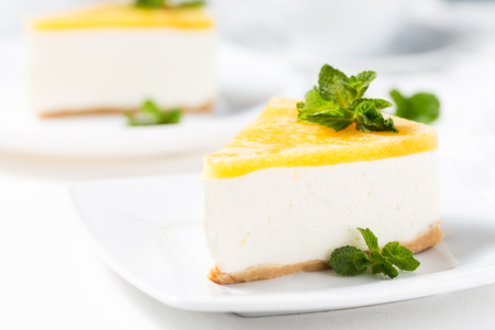 No-bake cheesecake decorated peach jelly and mint leaves on a white plateの写真素材