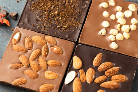 Handmade chocolate bars with nuts and coffee beans, top view