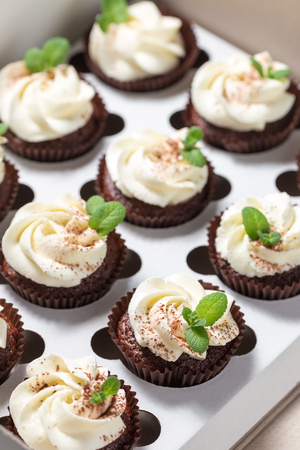 Chocolate cupcakes with cheese and mint leaves in a delivery boxの写真素材
