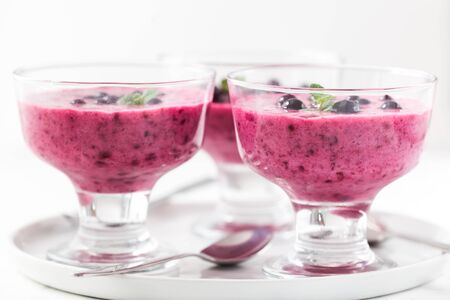 Homemade yogurt with black currants. Summer healthy dessert in glass bowlsの写真素材