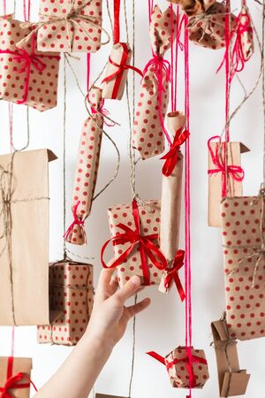 Handmade advent calendar hanging on a white wall. Child takes a gift, close up.の写真素材