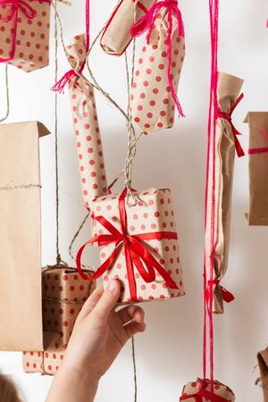 Handmade advent calendar hanging on a white wall. Child takes a gift, close up.の写真素材