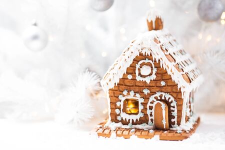 Homemade gingerbread house, white Christmas tree and garland light.の写真素材