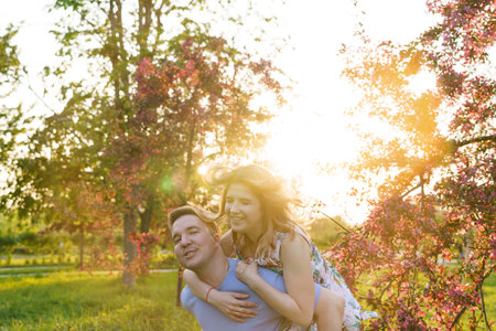A happy couple embrace a blooming orchard at sunset